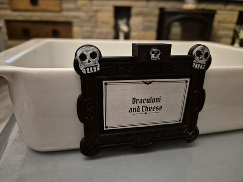 3D printed skulls buffet tag reading Draculoni and Cheese on a white ceramic dish